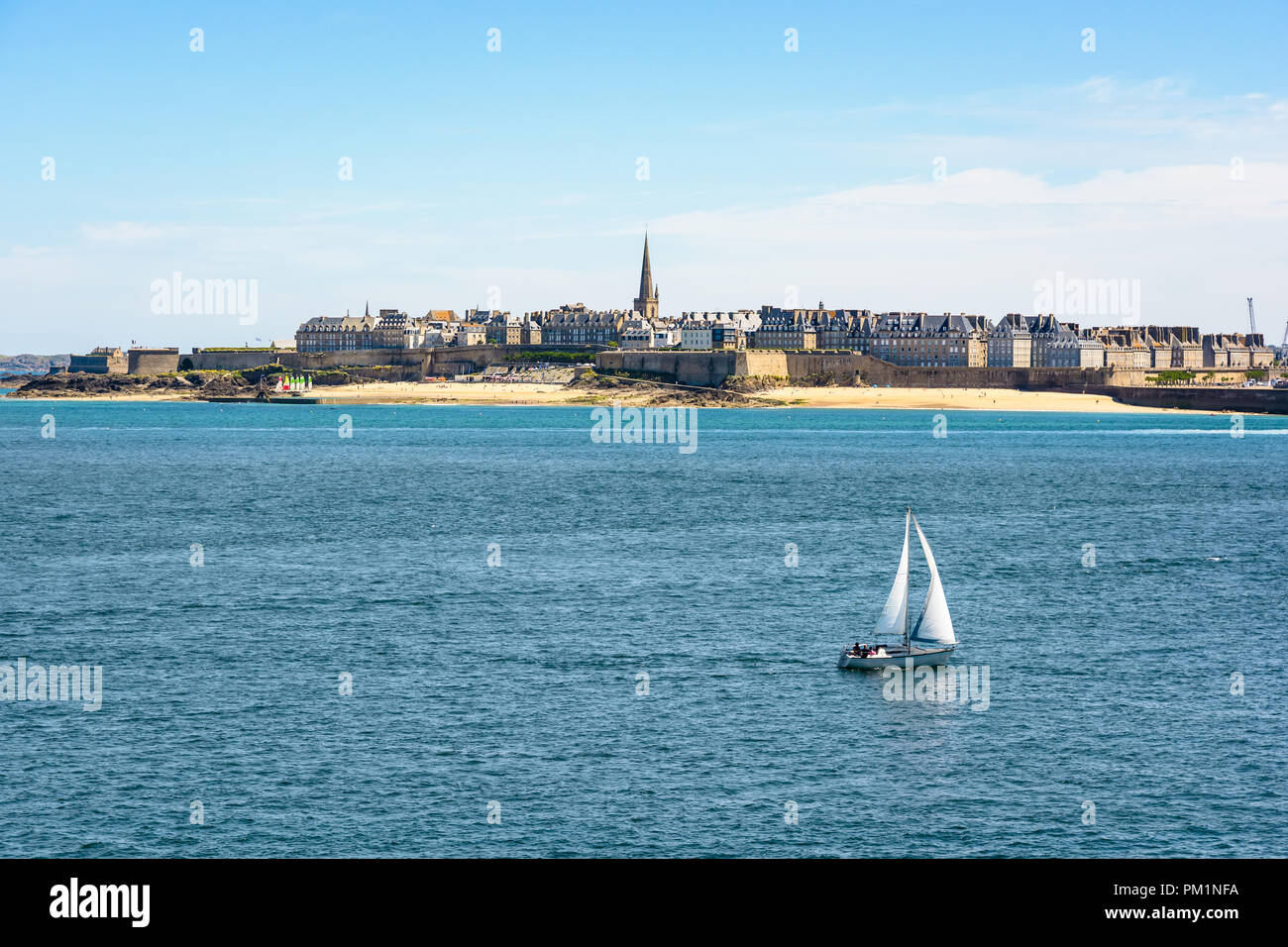 Die ummauerte Stadt Saint-Malo in der Bretagne, Frankreich, mit dem Dom ragt über dem Gebäude hinter der Wand und ein Boot Segeln auf dem Meer. Stockfoto