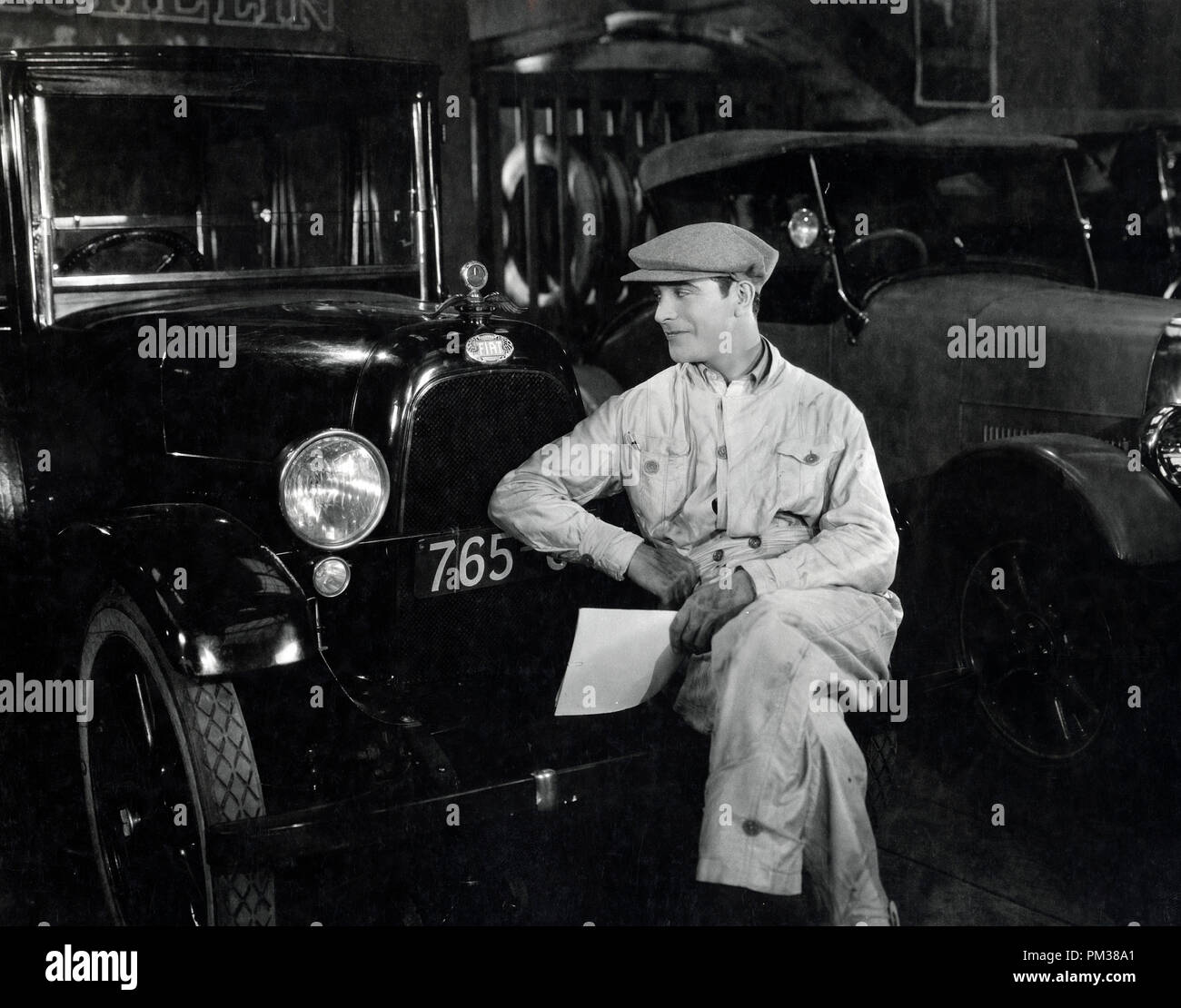 Stummfilm Szene immer noch. Ein Automechaniker in Latzhosen, ruht auf der Stoßstange eines Fahrzeugs aus den 1920er Jahren, ca. 1930. Datei Referenz Nr. 1183 014 THA Stockfoto