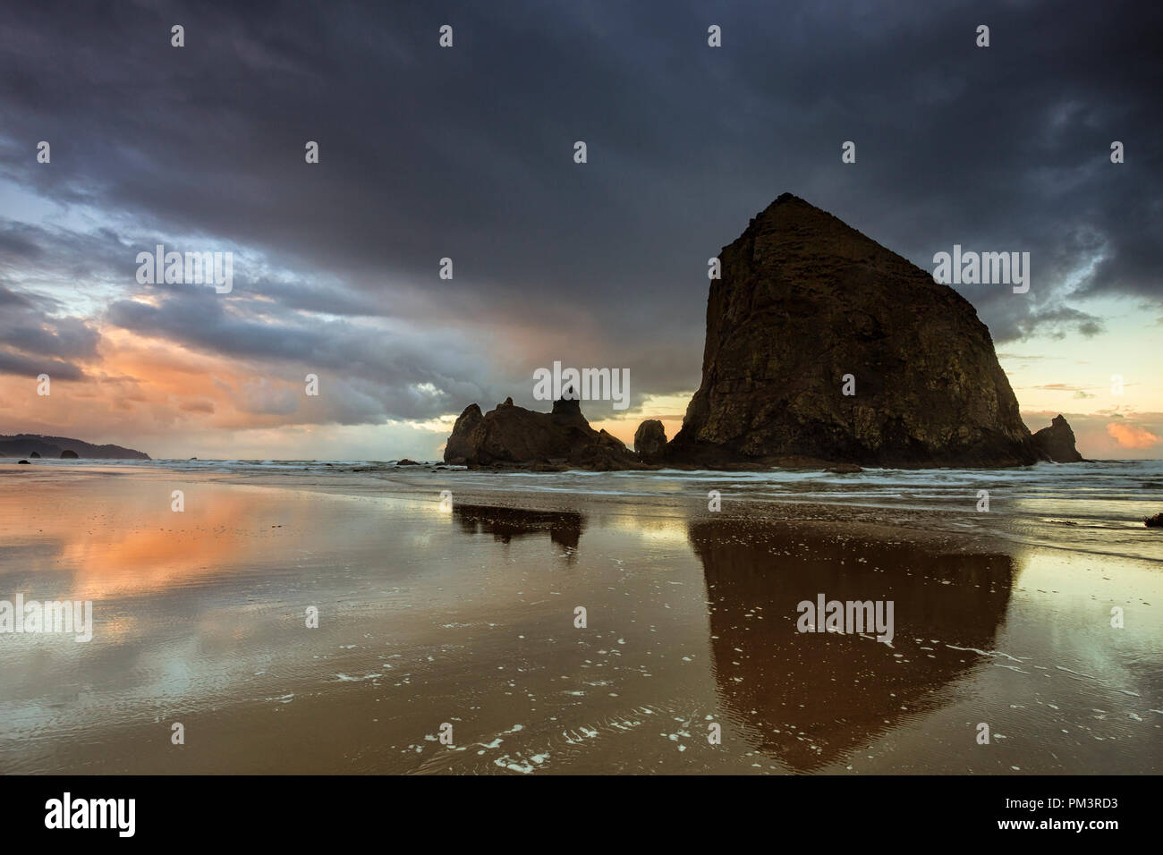 Des Oregon Haystack Rock entlang Cannon Beach am Abend Stockfoto