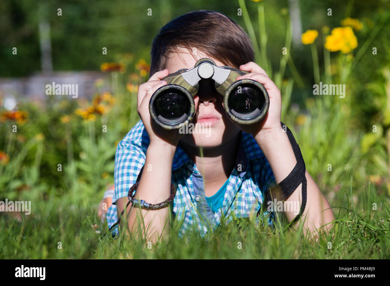 Junge junge Forscher erkunden mit Fernglas Umgebung im grünen Garten Stockfoto