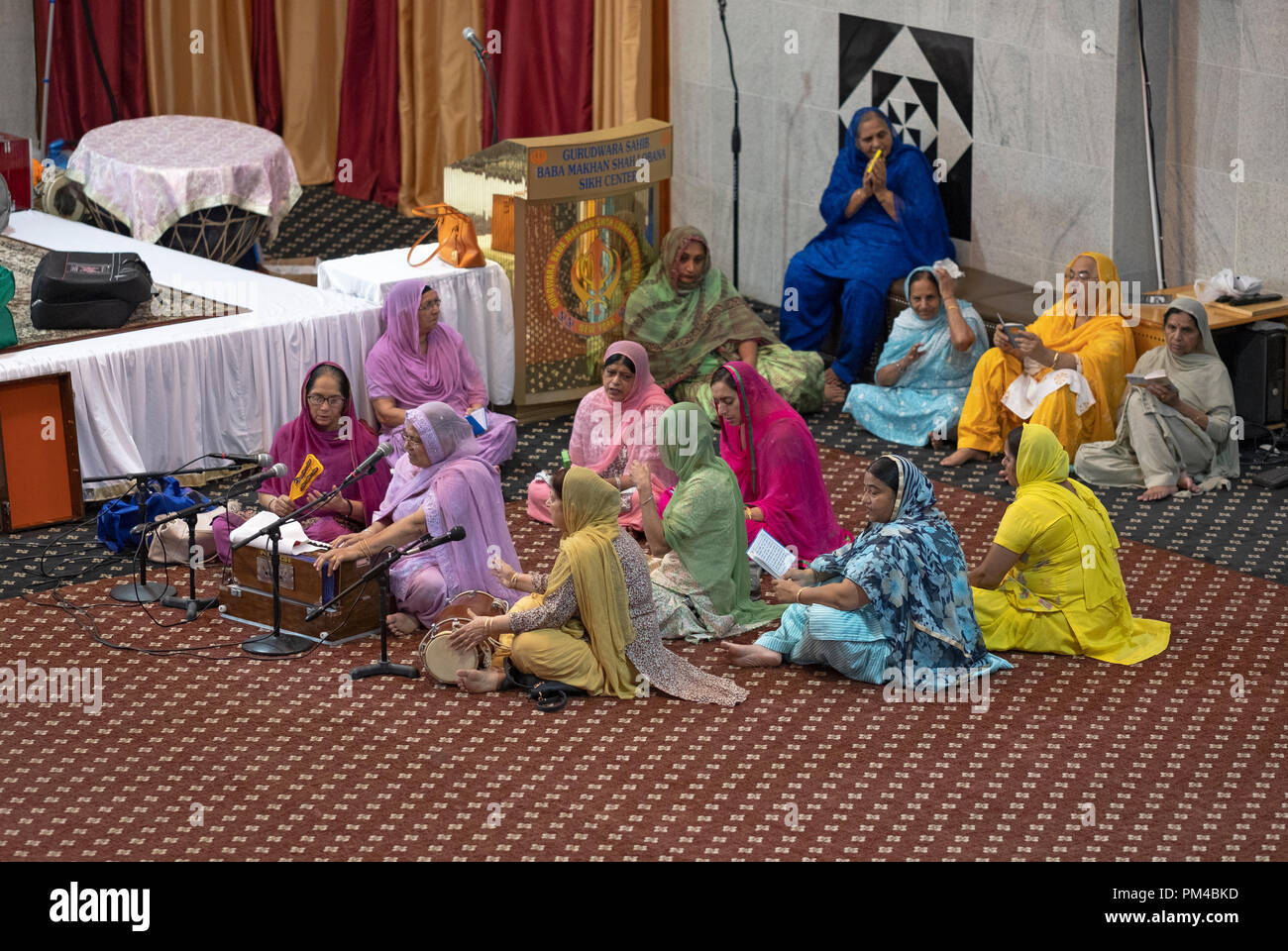 Eine Gruppe von Frauen zu beten, meditieren und Musik zu spielen Baba Makhan Shah Lobana Tempel in Queens, New York. Stockfoto