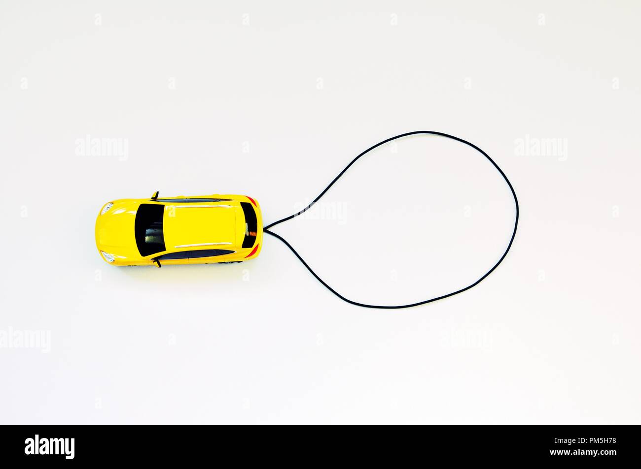 Spielzeug gelb Auto auf weißem Hintergrund mit Kopie Raum mit einem schwarzen Kabel erstellt. Ansicht von oben Stockfoto