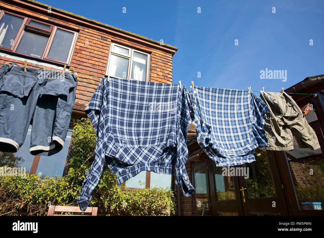 Überprüft Shirts und Shorts hängen draußen auf einer Wäscheleine trocknen an einem windigen Tag Stockfoto