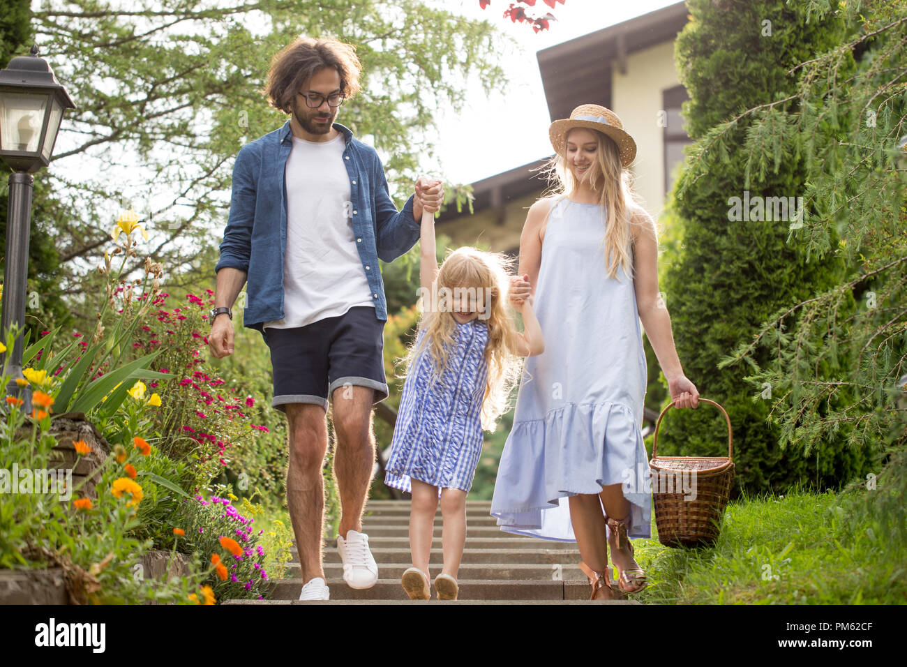 Junge Familie mit Korb nach Picknick zu Fuß über Treppen außerhalb im Green Park Stockfoto