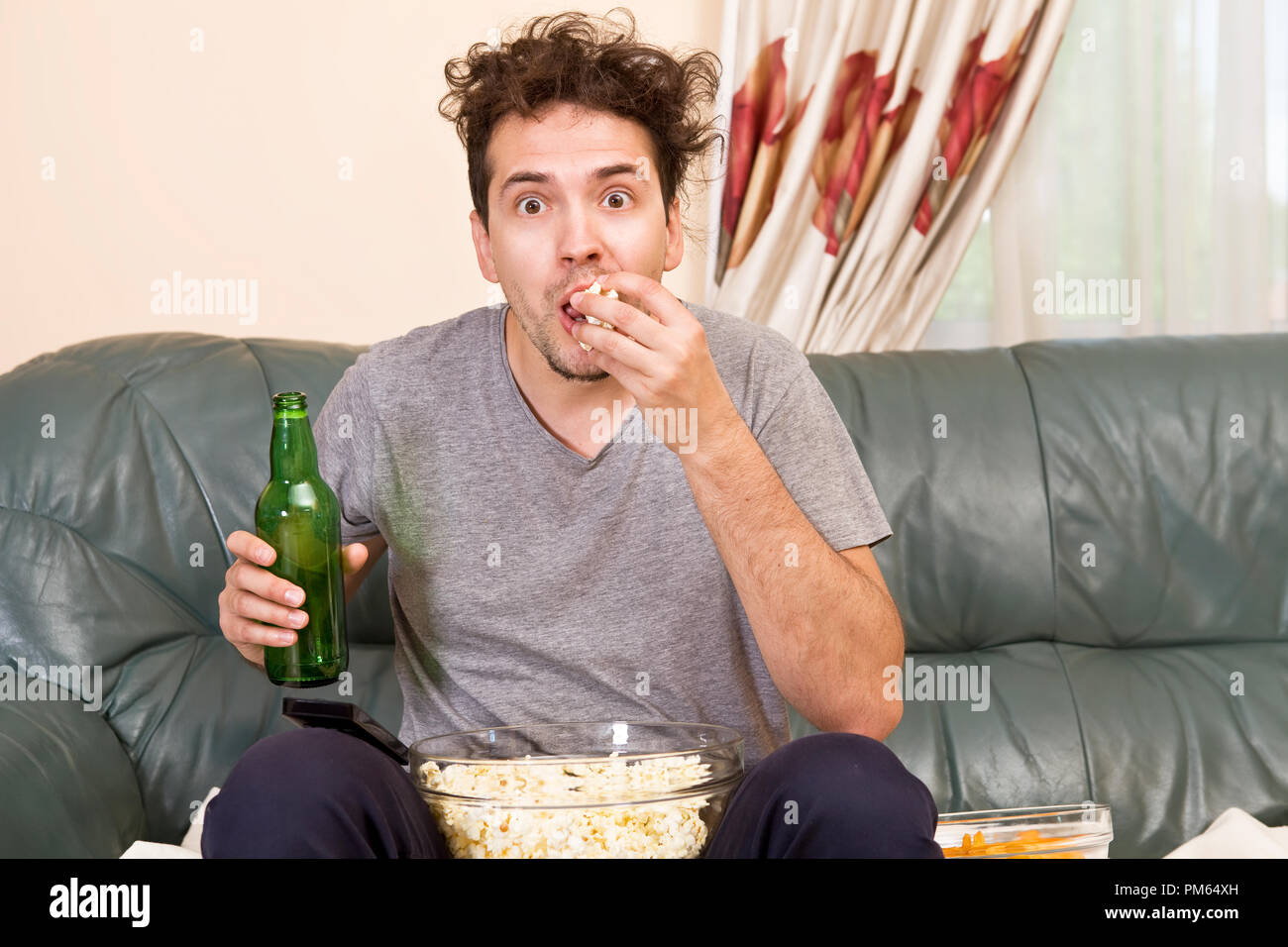 Mann mit Bier und Chips vor dem Fernseher zu Hause Stockfoto