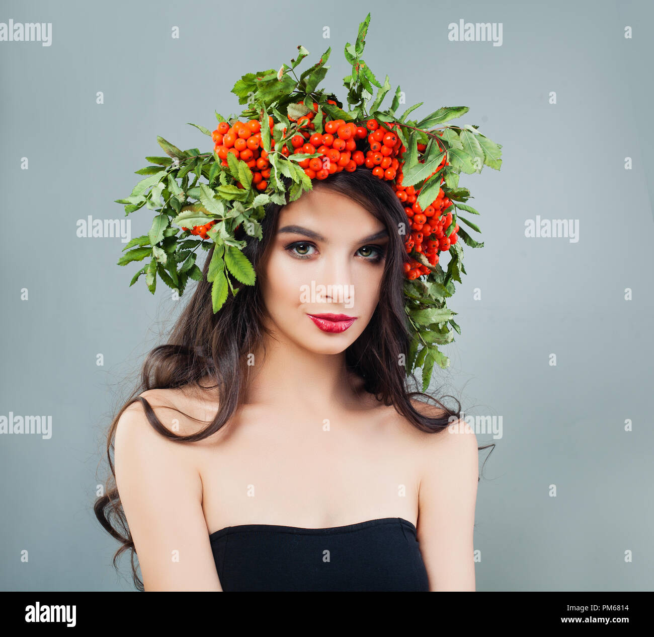 Junge Frau mit Make-up-niedlich, gewellten braunen Haar und roten Beeren und Blätter in Frisur Stockfoto