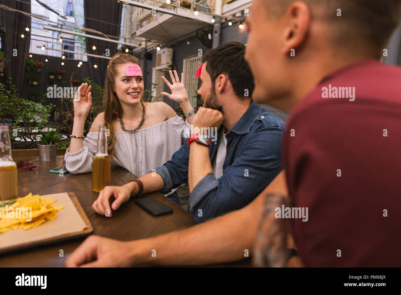 Expressive junge Frau lächelnd und Spielen mit Freunden Stockfoto