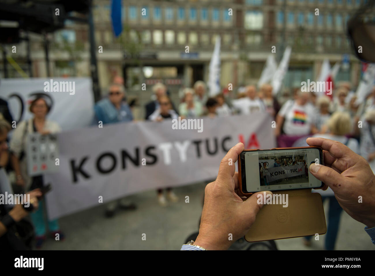 Ein Mann gesehen, die Bilder mit einem Handy von Polen protestieren während der Demonstration. Polen in Warschau protestiert gegen den Bruch der Verfassung und die Politisierung des Obersten Gerichts von der polnischen Regierung (durch PiS regierte - Recht und Gerechtigkeit) und der Präsident (Andrzej Duda) von Polen. Am Ende des März die Straße Opposition ein Shirt mit dem Konstytucja (Verfassung) Wort für das Denkmal des Königs Sigismund die Spalte auf dem Schlossplatz der Altstadt von Warschau gelegen gehängt. Stockfoto