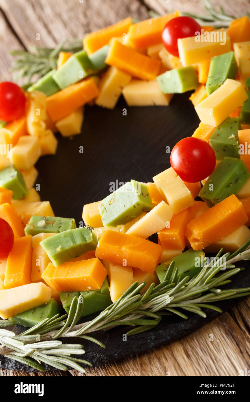 Schöne Weihnachten Vorspeise mit verschiedenen Käse mit Tomaten in der Form eines Kranzes close-up auf dem Tisch. Vertikale Stockfoto