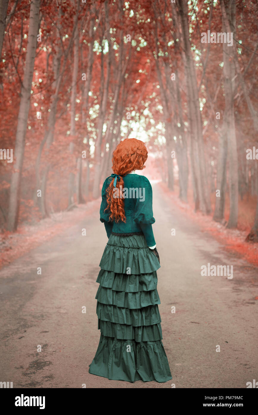 Viktorianische Frau, die auf der Landstraße mit Bäume im Herbst Stockfoto