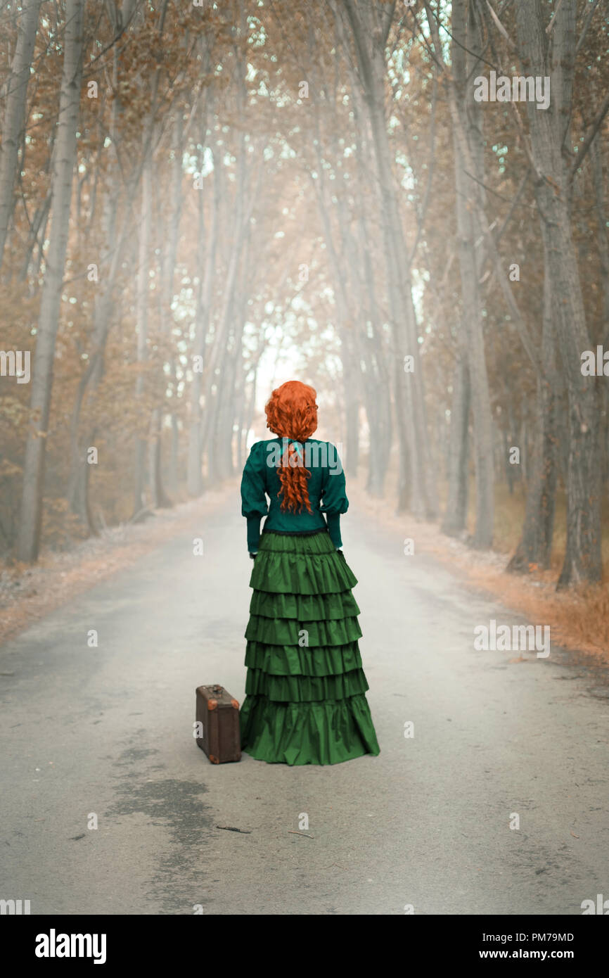 Viktorianische Frau, die auf der Landstraße mit Bäume im Herbst Stockfoto