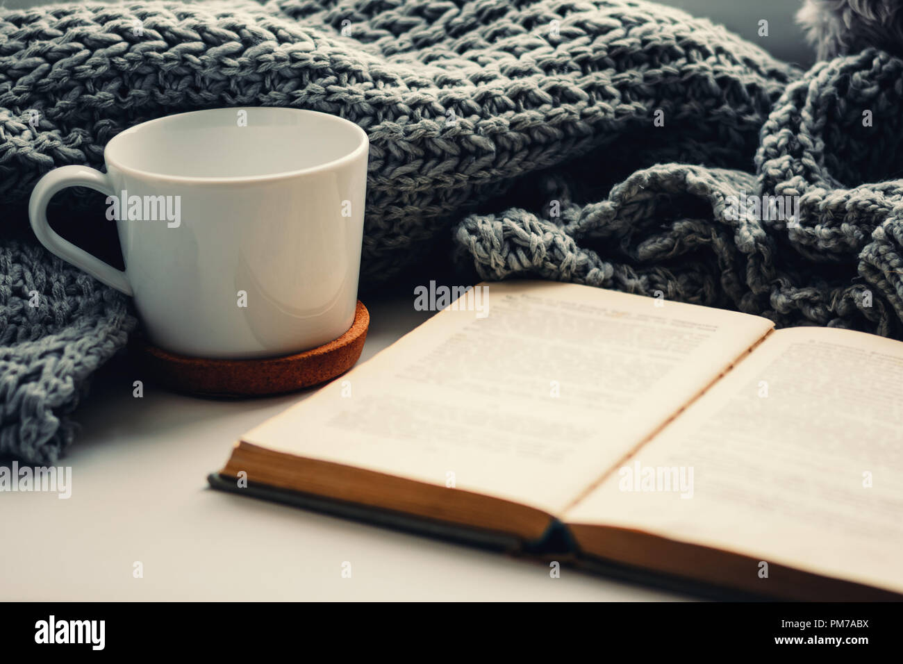 Wollschal, Tasse Tee und Buch auf der Fensterbank. Hygge und gemütliche Herbst Konzept Stockfoto