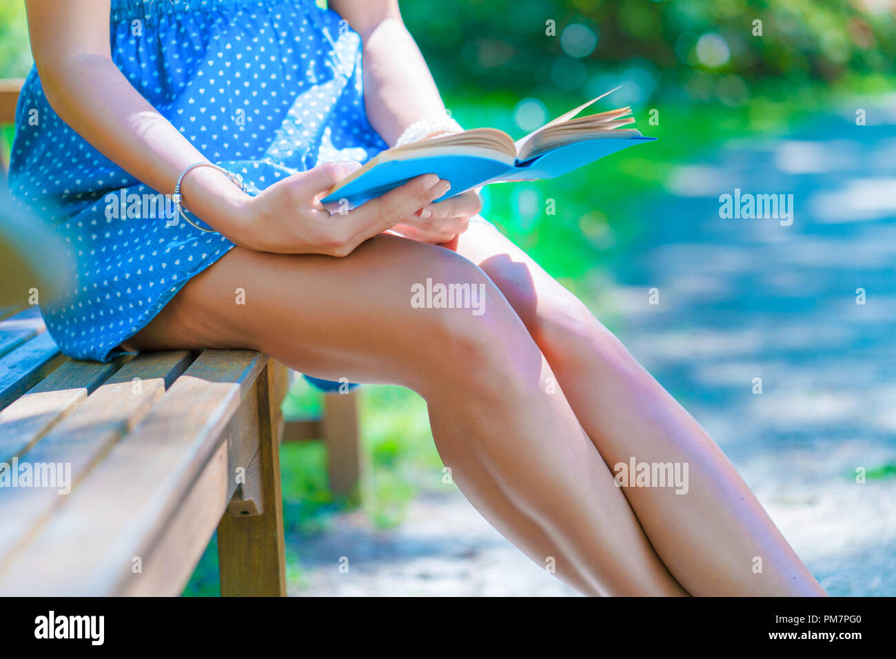Mädchen mit Kleid mit einem Buch auf einer Parkbank Stockfoto