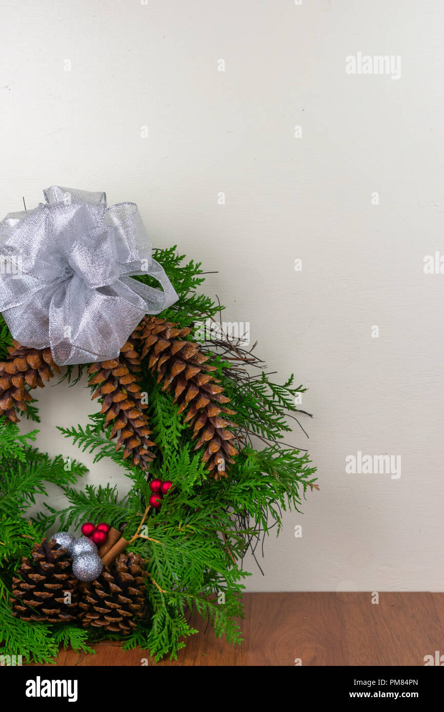 Weihnachten ein Kranz mit Zeder Äste, Tannenzapfen, Zimtstangen, Silber Schmuck und rote Beere Cluster mit einem Silver Bow auf der Oberseite Stockfoto