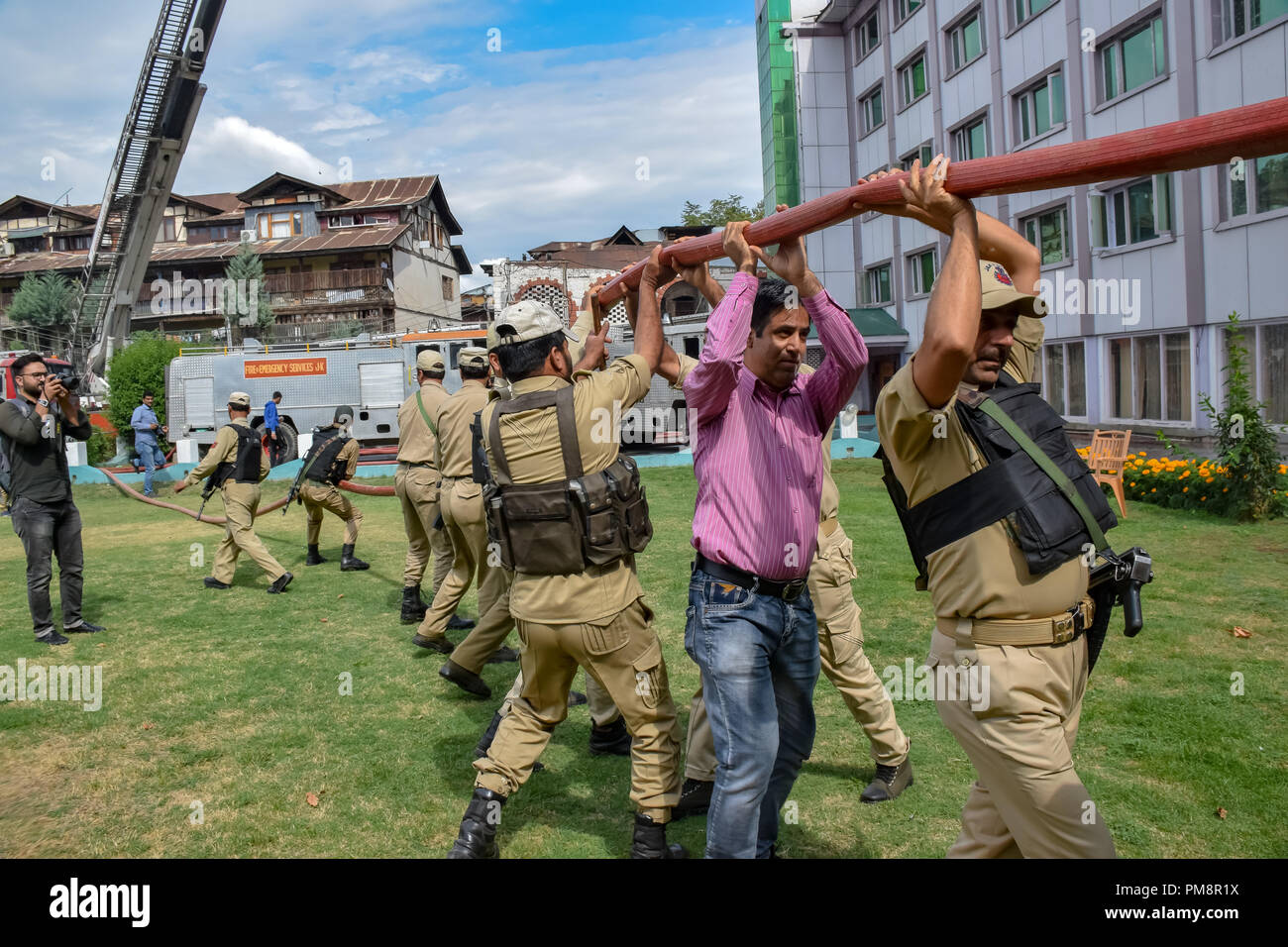 Regierung und einem lokalen Mann gesehen ziehen eine Wasserleitung zu bekommen es in der Nähe das Hotel Gebäude in Brand verschlungen. Ein massives Feuer brach in einem lokalen Hotel hier in Fairbanks am Samstag, aber es war kein Verlust des Lebens oder Verletzungen, teilte die Polizei mit. Feuer Angebote wurden an Ort und Stelle und Polizei hetzte, und Feuerwehr- und Rettungsdienste versuchten, die Flammen zu löschen. Stockfoto