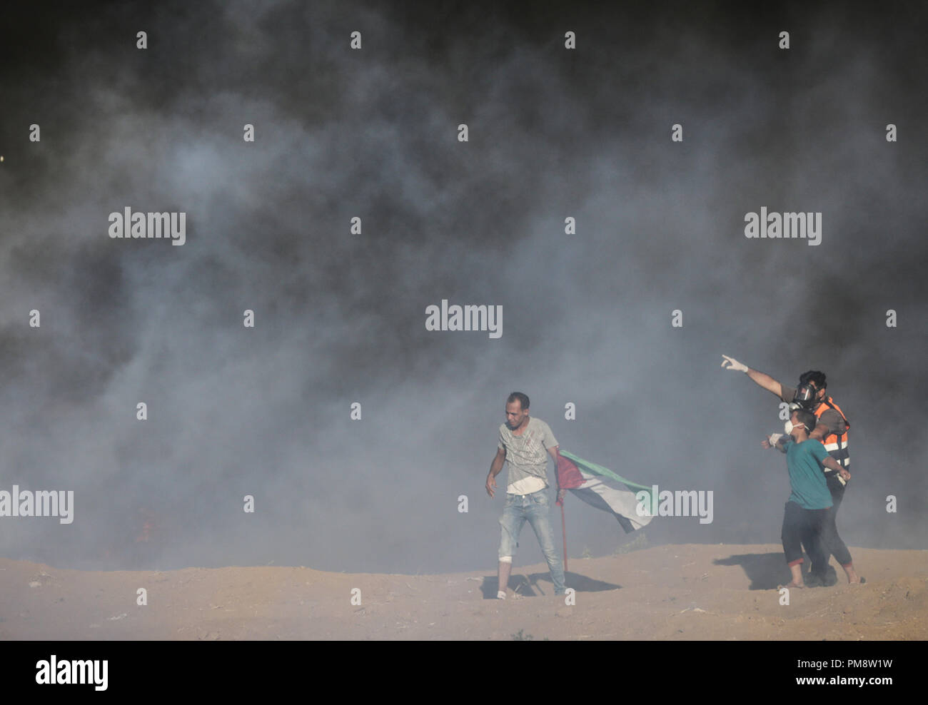 Retter und ein demonstrant gesehen mit Rauch während der zusammenstöße abgedeckt. Auseinandersetzungen zwischen palästinensischen Demonstranten und israelischen Kräfte während eines Protestes entlang der israelischen Zaun östlich von Gaza-stadt. Stockfoto