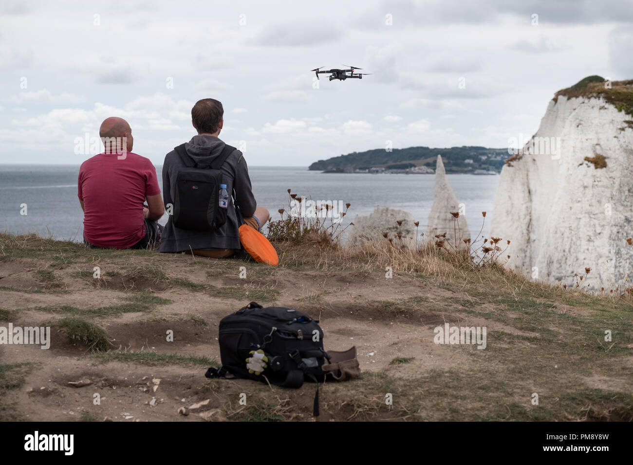 Ein Mann gerade eine Drohne schwebte er weg Fliegen ist auf einer Klippe an  der englischen Küste. wird er von einem anderen Mann neben ihm saß,  begleitet Stockfotografie - Alamy