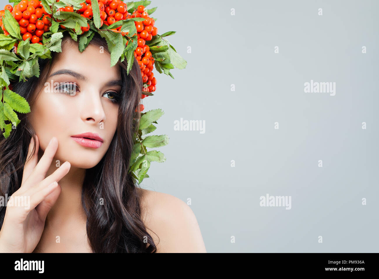 Schöne Frau mit natürlichen Make-up, perfekte Haut, gesunde Haare und grüne Blätter auf Hintergrund mit Kopie Raum Stockfoto