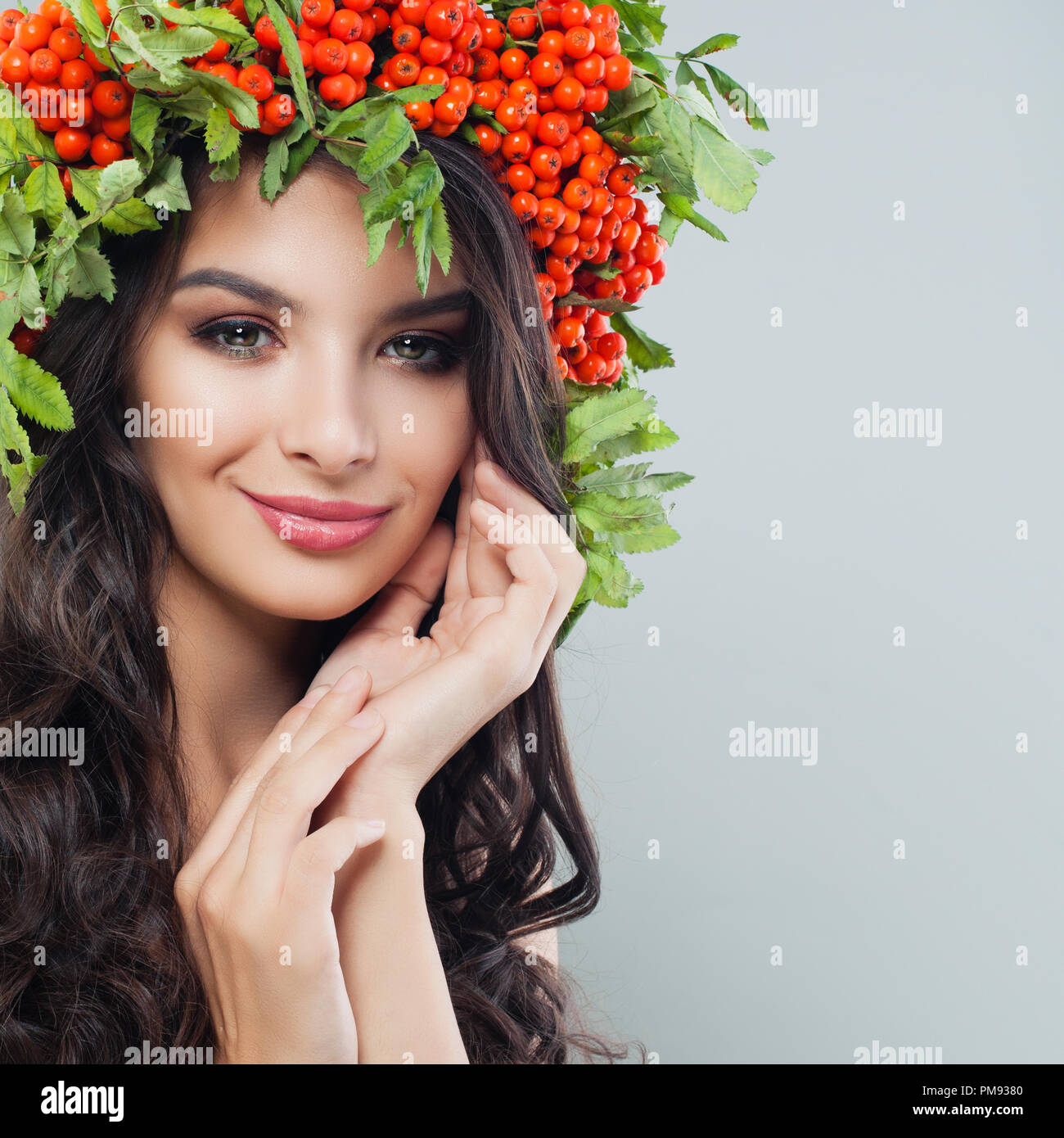 Junge hübsche Frau mit langen gewelltes Haar, gesunde Haut und rote Beeren und Blätter Kranz Stockfoto