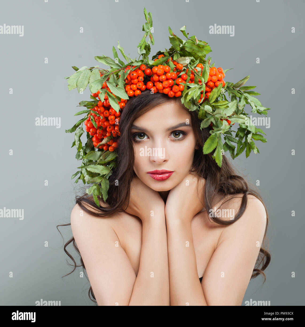 Brünette Frau mit gesunden curly Frisur, Make-up und roten Beeren und grüne Blätter, Porträt Stockfoto