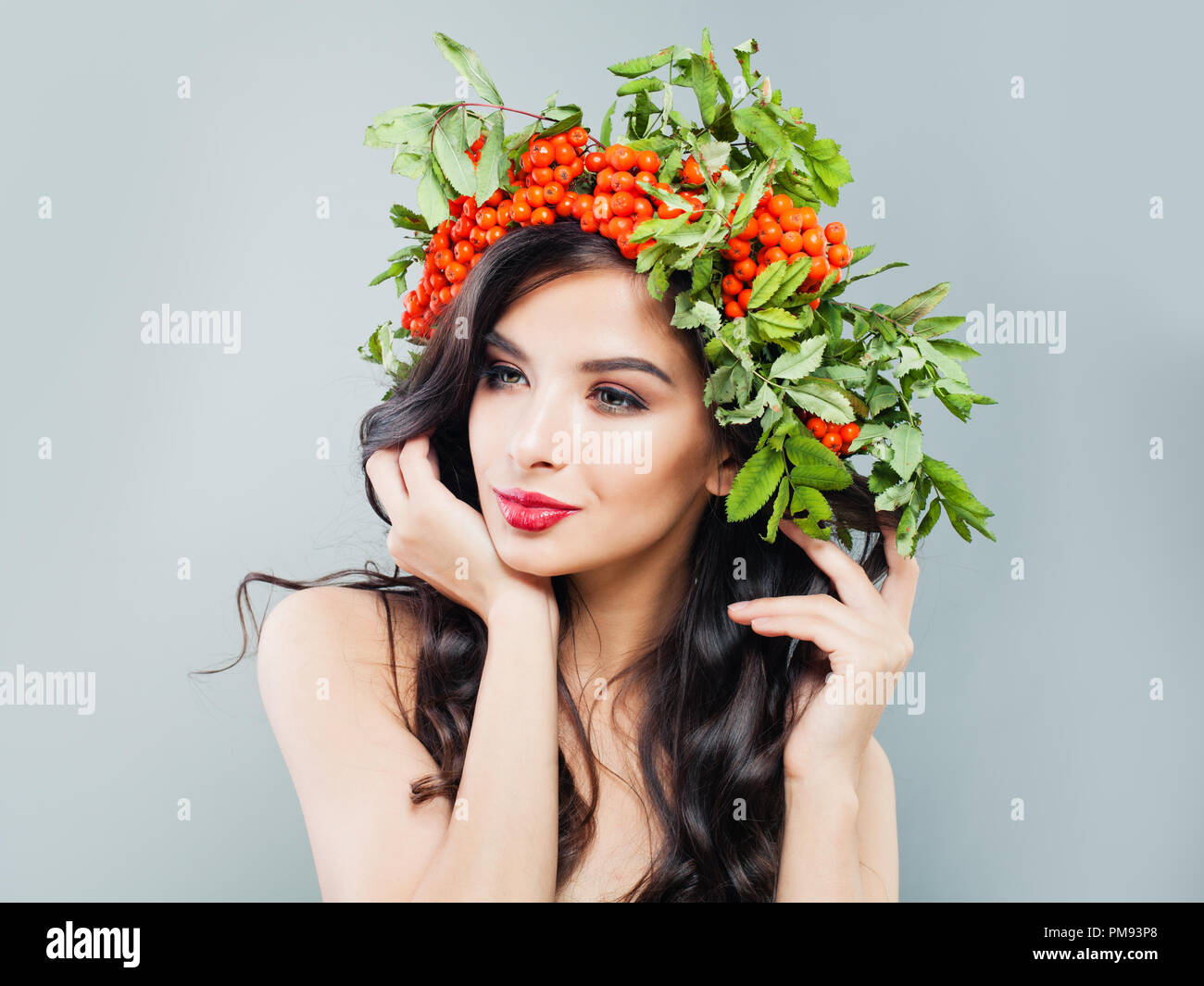 Gesunde Frau Brünette mit gewellten Frisur, Make-up und roten Beeren und grüne Blätter Stockfoto