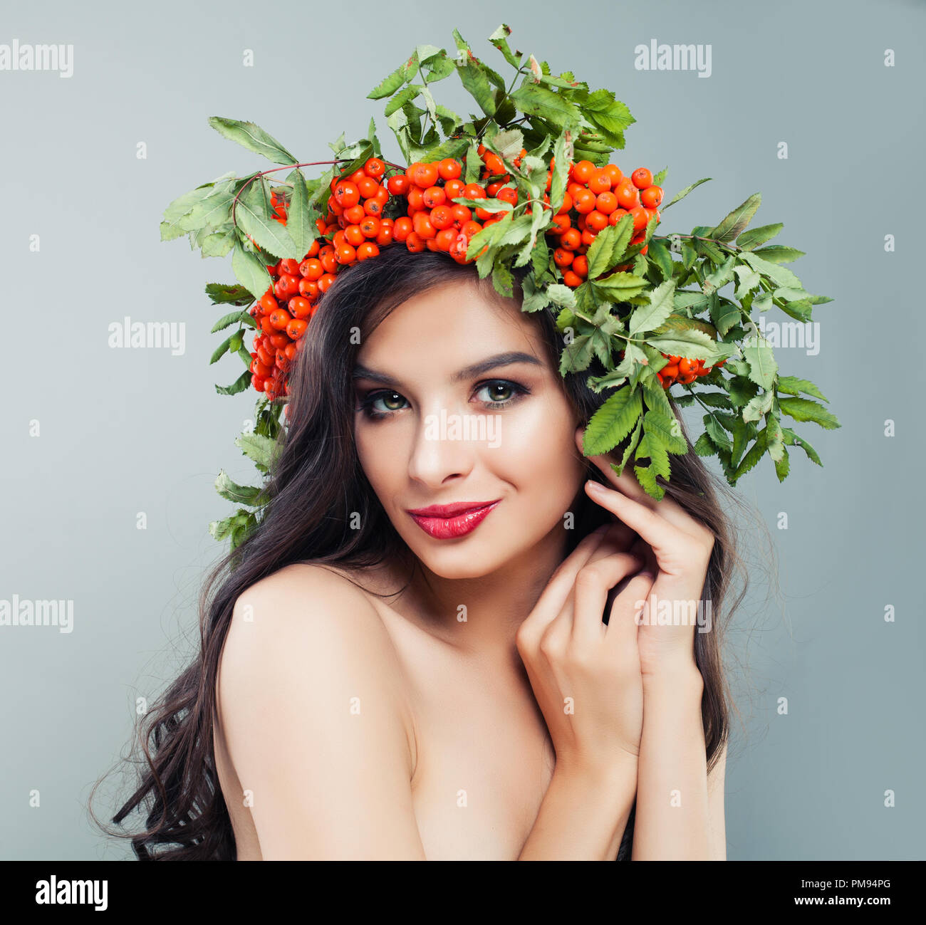 Schöne Frau mit gesunden curly Frisur, Make-up und roten Beeren und grüne Blätter, Porträt Stockfoto