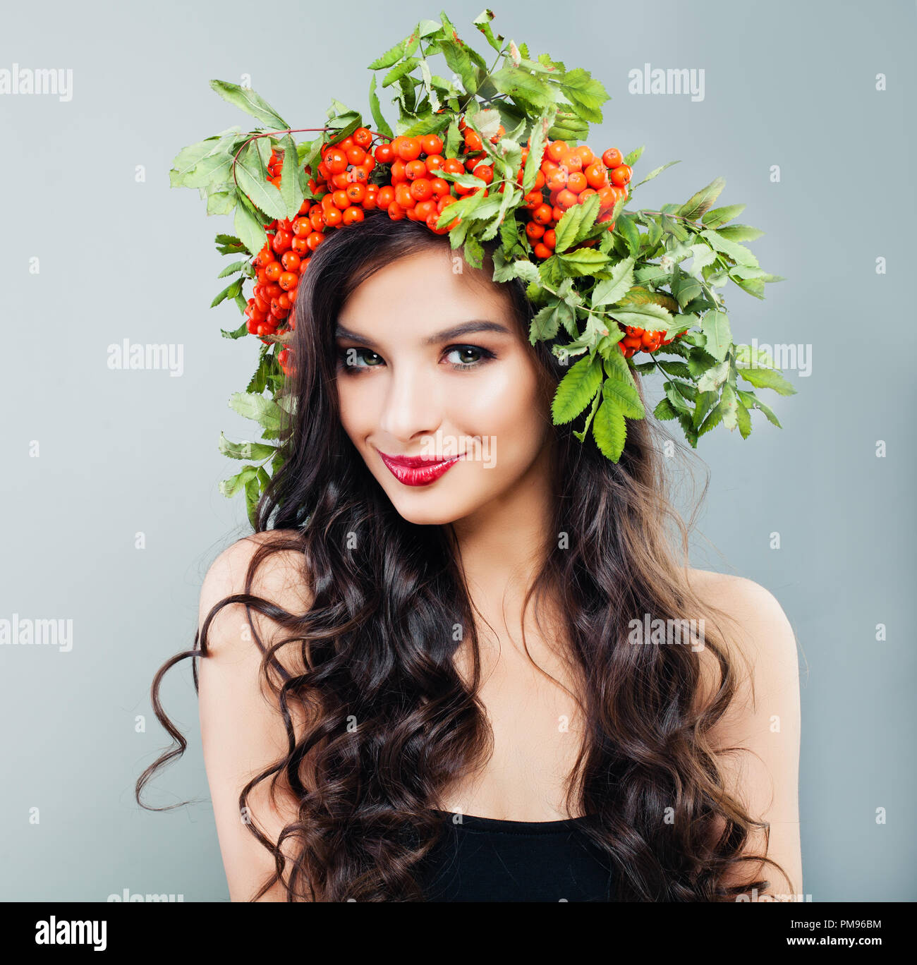 Happy brunette woman fashion Modell mit gesunden curly Frisur, Make-up und roten Beeren und grüne Blätter, Porträt Stockfoto