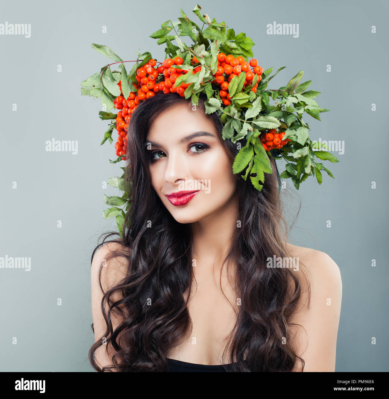 Attraktive Frau mit gesunden curly Frisur, Make-up und roten Beeren und grüne Blätter, Porträt Stockfoto