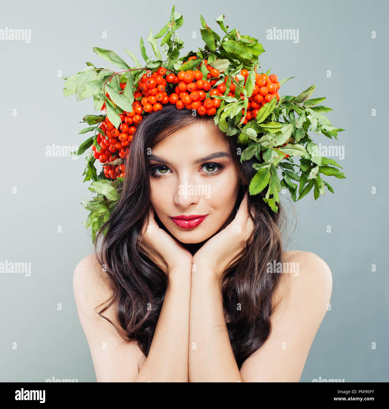 Brunette Mädchen fashion model mit Makeup und roten Beeren und grüne Blätter, Porträt Stockfoto
