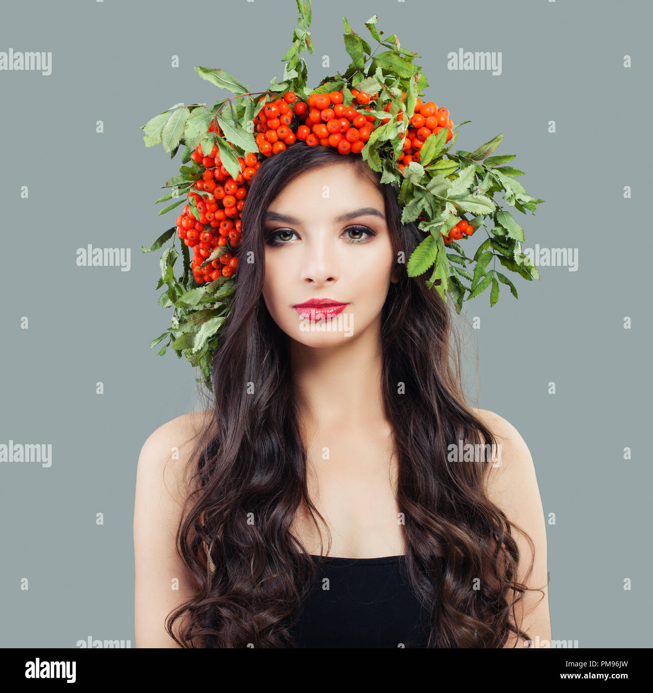 Attraktive Frau mit Make-up, lange wellige Haare und rote Beeren und Blätter Kranz Stockfoto