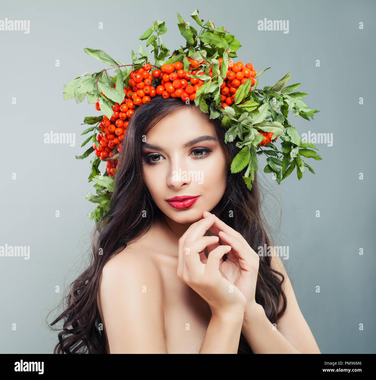 Attraktive brünette Frau mit gesunden curly Frisur, Make-up und roten Beeren und grüne Blätter Stockfoto