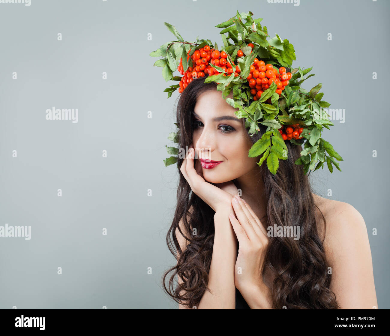 Pretty Woman Fashion Model mit gesunden curly Frisur, Make-up und roten Beeren und grüne Blätter Stockfoto