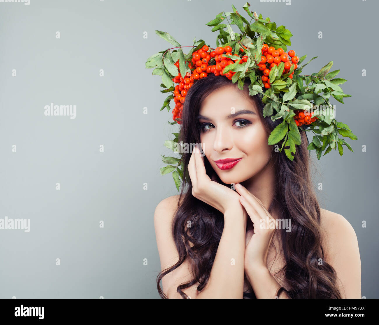 Süß lächelnde Frau Mode Modell mit gesunden curly Frisur, Make-up und roten Beeren und grüne Blätter, Porträt Stockfoto
