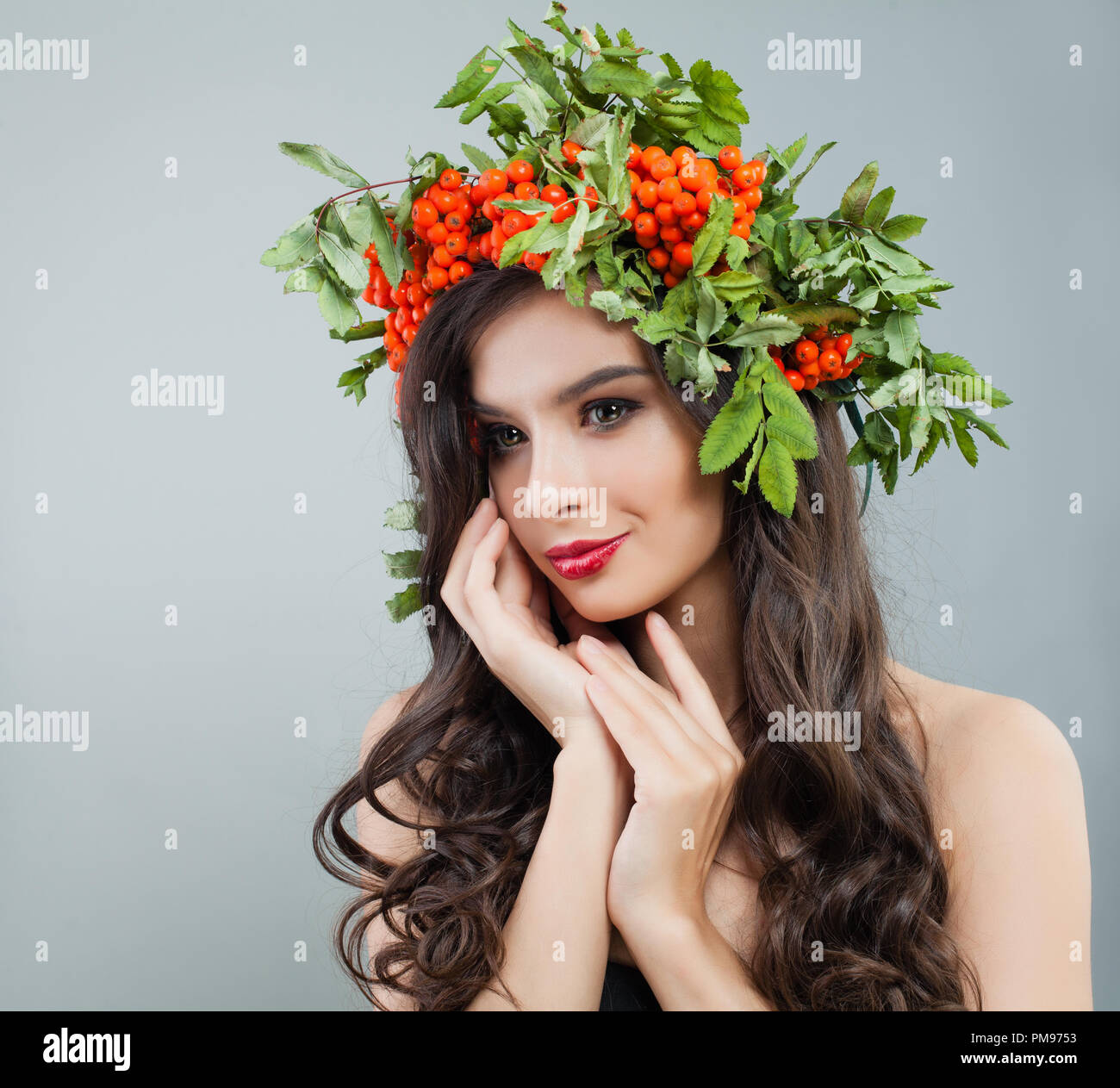 Glückliche junge Frau mit gesunden curly Frisur, Make-up und roten Beeren und grüne Blätter Stockfoto
