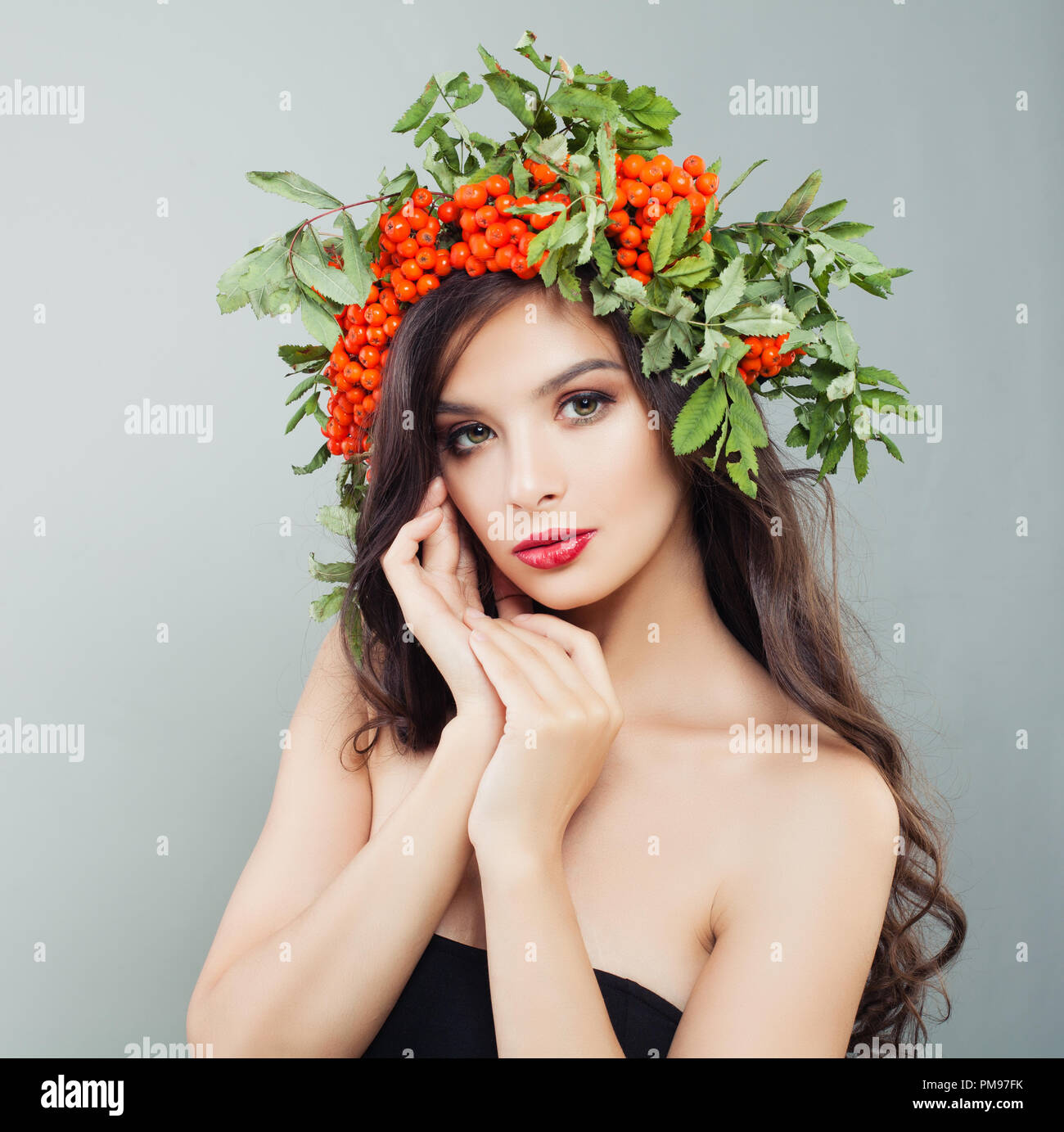 Nette junge Frau Porträt. Mädchen mit gesunden curly Frisur, Make-up und roten Beeren und grüne Blätter Stockfoto