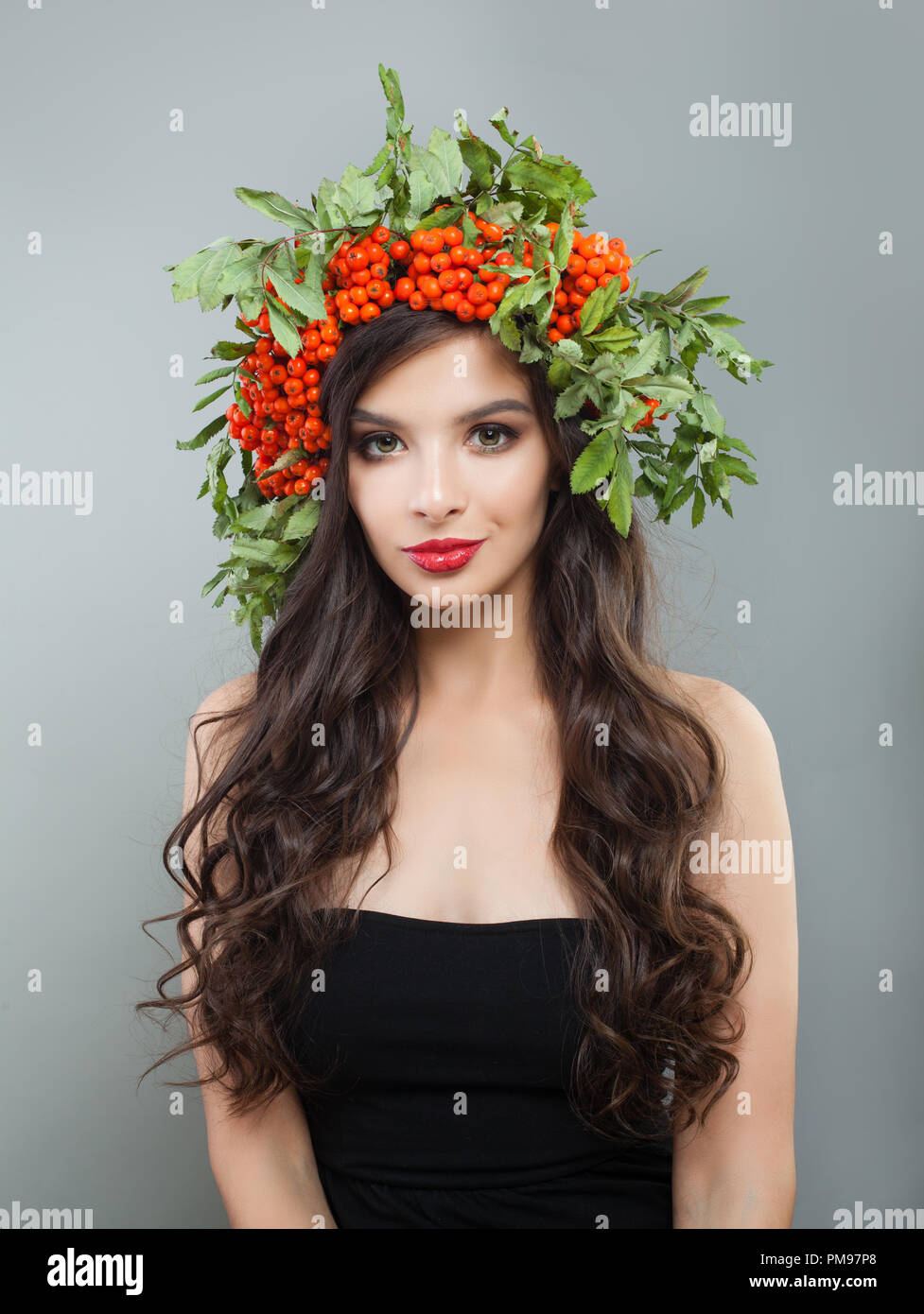 Brunette woman fashion Modell mit gesunden curly Frisur, Make-up und roten Beeren und grüne Blätter Stockfoto
