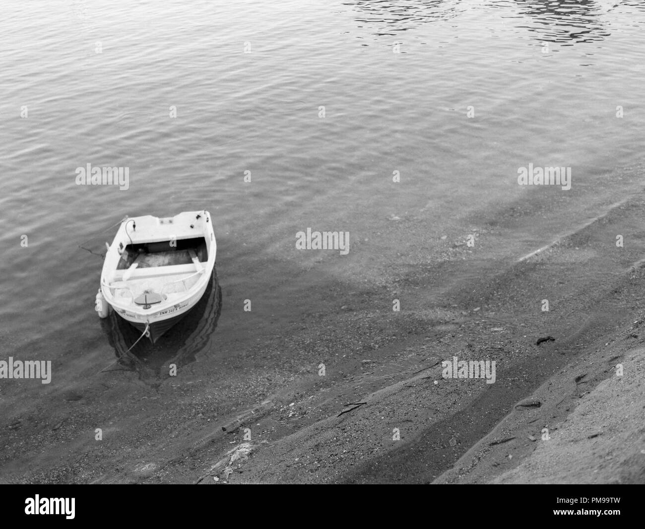 Kleines Motorboot vor Anker auf Schwarz-Weiß-Film gedreht Am Strand in Griechenland Stockfoto