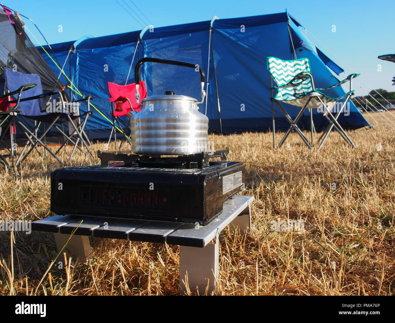 Ein Wasserkocher auf einem Gas- camp Backofen mit Zelten im Hintergrund Stockfoto