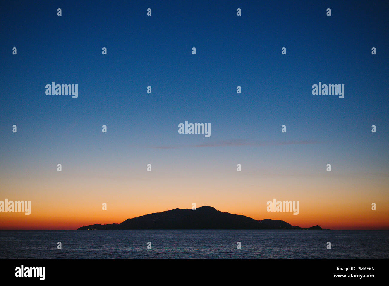 Eine kleine einsame Insel mitten im Ozean isoliert auf den Horizont gegen ein helles orange Sonnenuntergang. Silhouette. Stockfoto