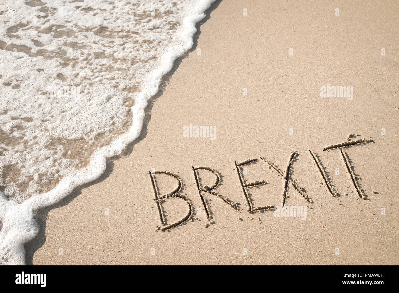 "BREXIT" in den Sand geschrieben am Strand mit Meerblick Waschmaschine bis zum Ufer. Stockfoto