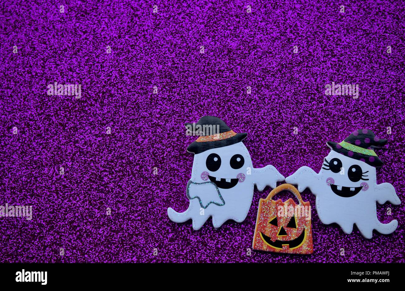 Zwei Geister mit einem Kürbis Trick oder Tasche auf einem violetten Hintergrund behandeln Stockfoto