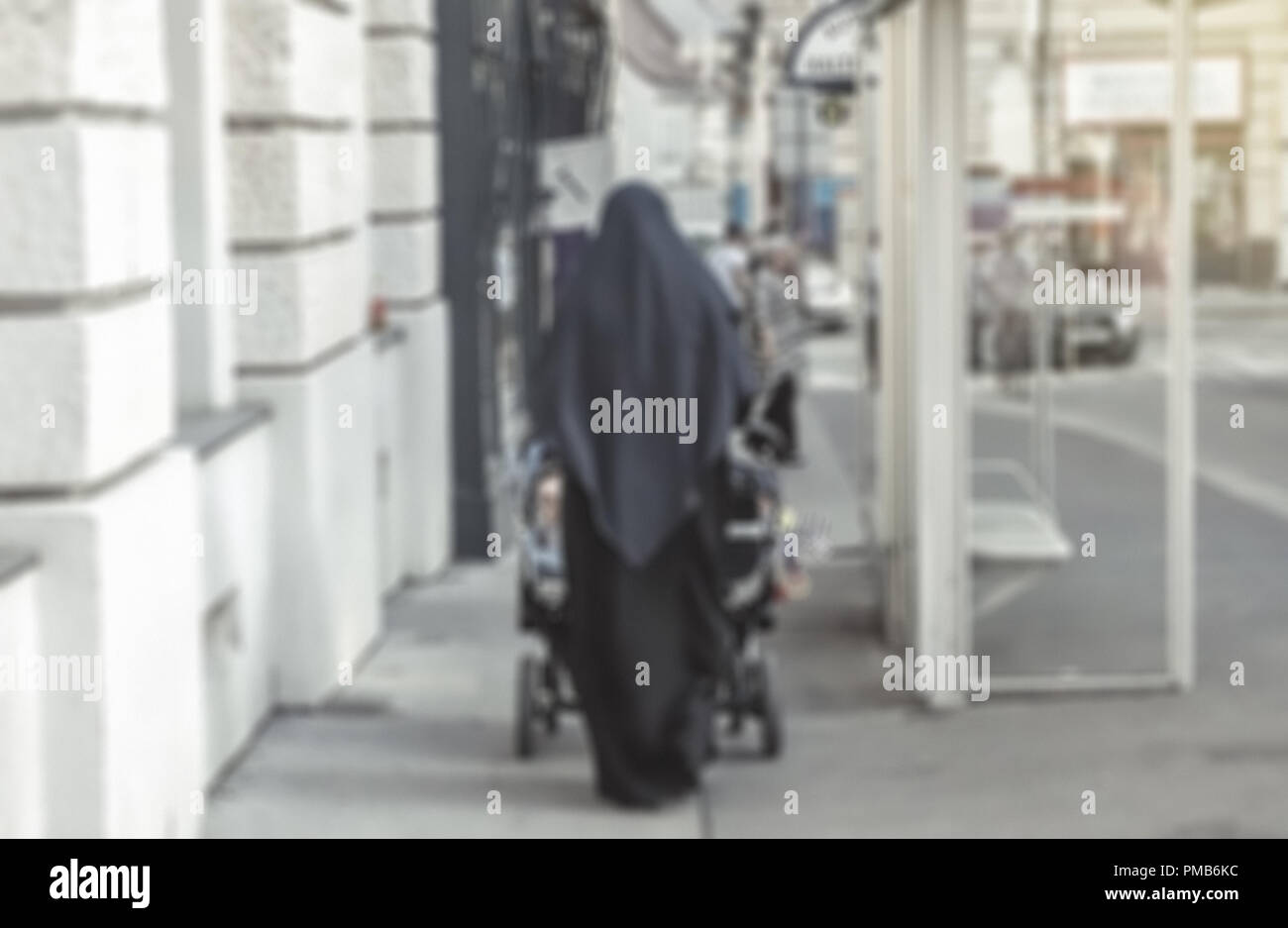 Nicht erkennbare muslimische Frau mit Schleier und schieben Kinderwagen in Europäischen Stadt verwischt Stockfoto