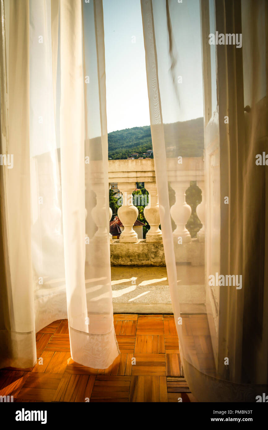 Fließende Gardinen wehen im Wind, als sie zu der alten Europäischen hotel Balkon mit Blick schaffen eine romantische Atmosphäre in Opatija, Kroatien führen. Stockfoto