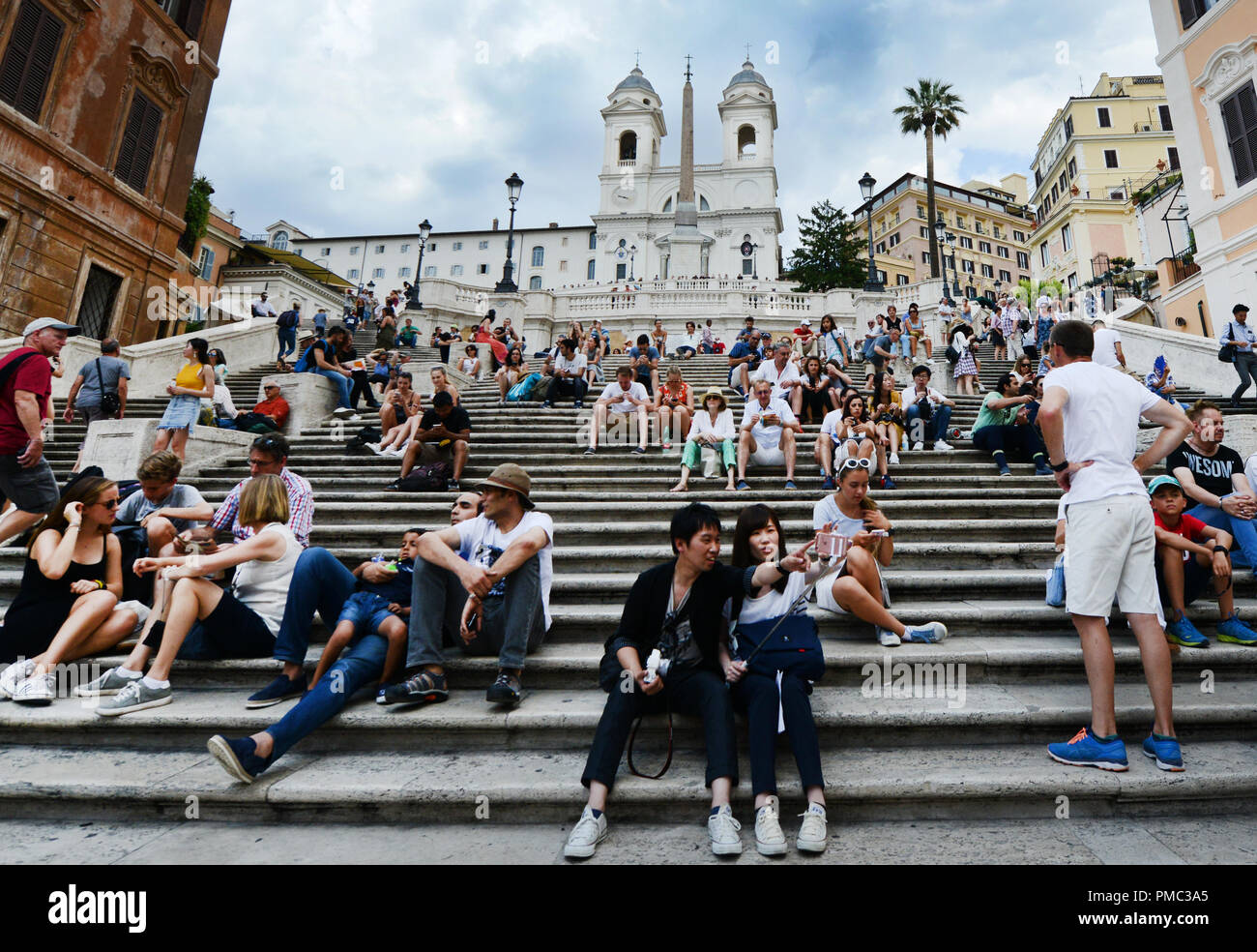 Touristen sitzen auf der Spanischen Treppe und genießen den Blick auf die Piazza di Spagna. Stockfoto