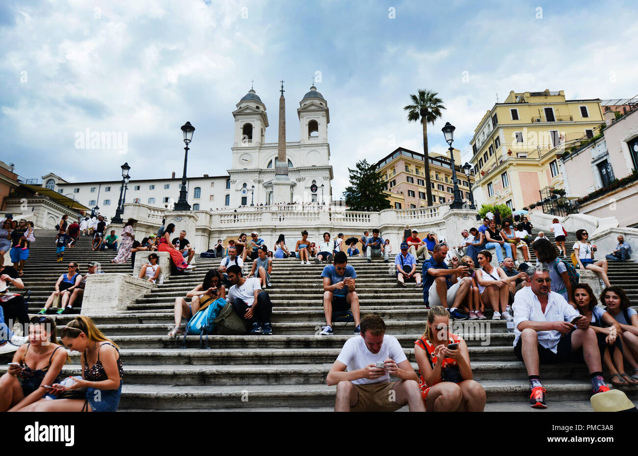 Touristen sitzen auf der Spanischen Treppe und genießen den Blick auf die Piazza di Spagna. Stockfoto