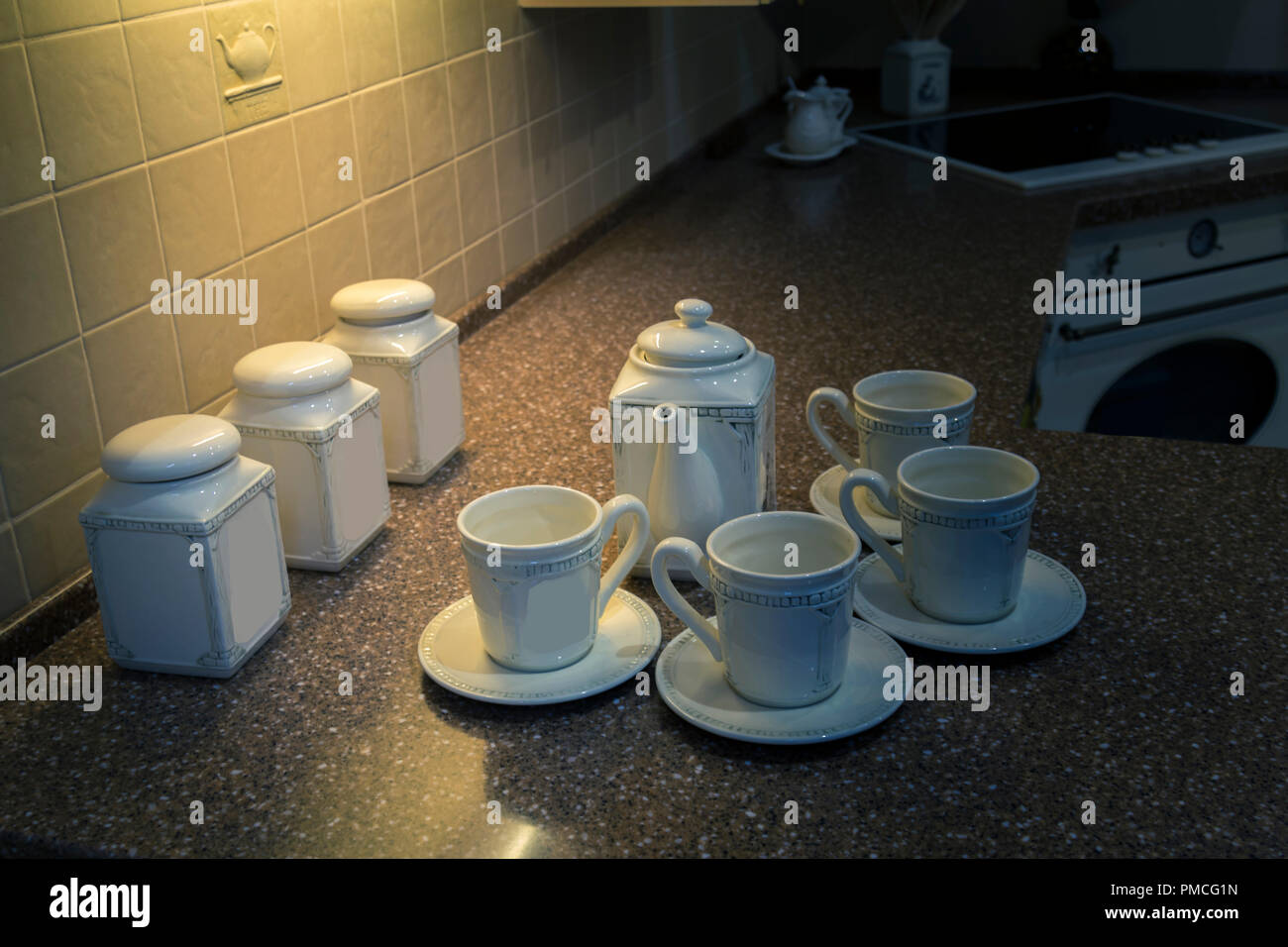 Teeservice aus Porzellan weiß auf einem Tisch mit künstlichem Licht beleuchtet Stockfoto