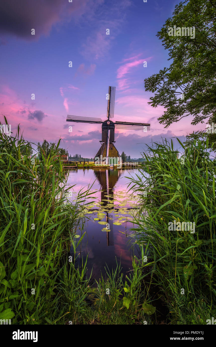 Alte holländische Windmühle und ein Kanal bei Sonnenuntergang in Kinderdijk, Niederlande. Dieses System der 19 Windmühlen wurde um 1740 erbaut und ist heute ein UNESCO Weltkulturerbe. Stockfoto