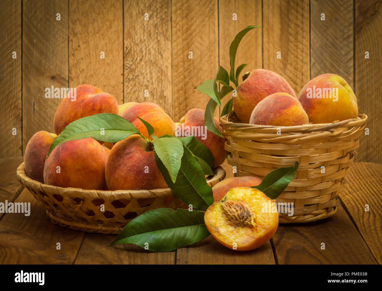Reif und schöne Pfirsiche in einem Korb auf einem hölzernen Hintergrund. Stockfoto
