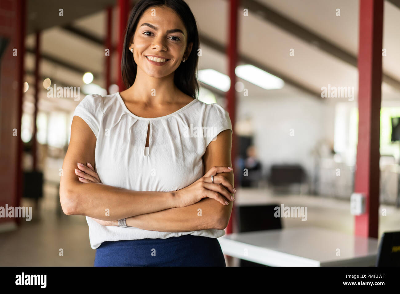 Lächelnd professionelle Geschäftsfrau in sportlich, mit gekreuzten Armen stehen im Amt. Stockfoto