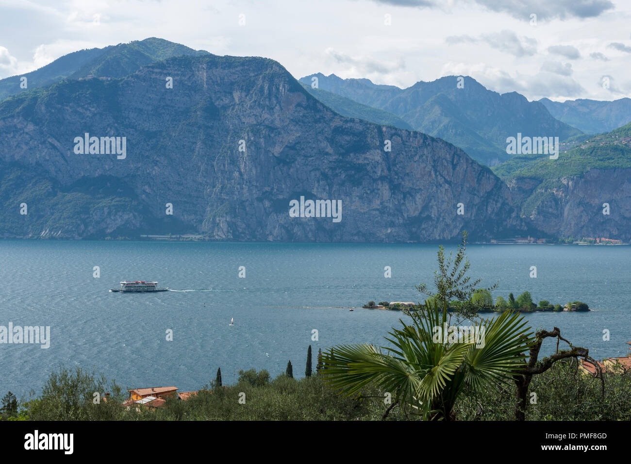 Aussicht über den Gardasee mit einem Boot überqueren und die Berge und einem bewölkten Himmel im Hintergrund, Bild vom oberen Teil des Dorfes Assenza di Brenzone auf Stockfoto